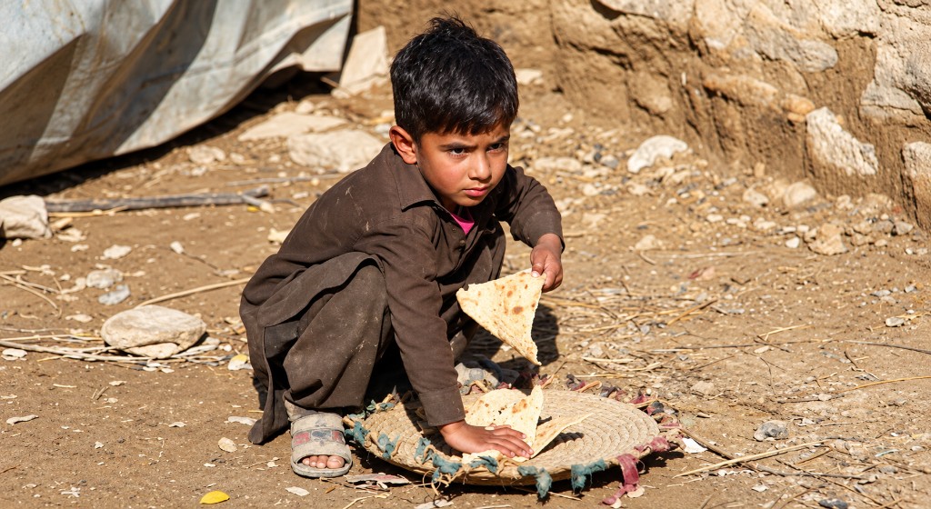 A boy with flatbread sitting on the ground